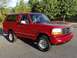 1995 Ford Bronco - This red Ford Bronco is shown from a three-quarter front view, parked outdoors.
