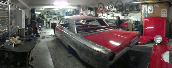 1964 Ford Fairlane body undergoing restoration in a garage, with red fenders and hood nearby