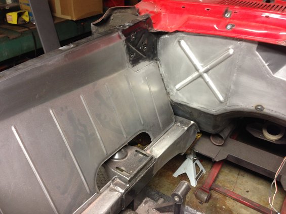 Close-up of a car's metal floor pan and inner fender well, showing repair work