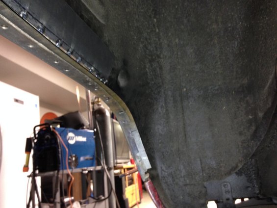 Wheel well interior with visible welding repairs and a Miller welding machine in the background