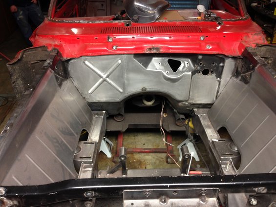 Car's engine bay stripped down for restoration. Firewall and inner fenders are visible