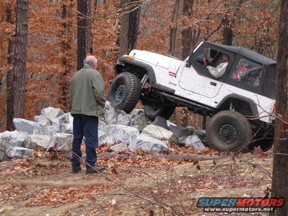 White Jeep Wrangler climbing over rocks on a trail