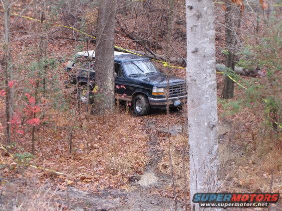 1992 Ford F-150 parked off-road between trees, yellow caution tape visible