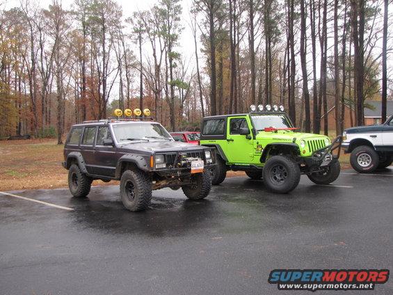 Dark SUV with yellow lights on roof rack and lime green Jeep Wrangler parked side-by-side