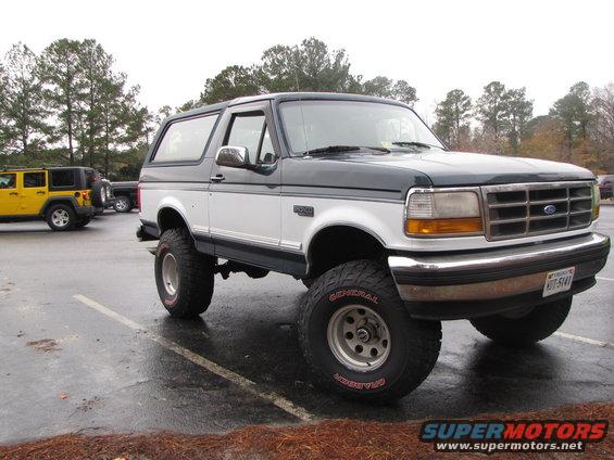 Two-tone Ford Bronco with aftermarket wheels and tires parked next to a yellow Jeep
