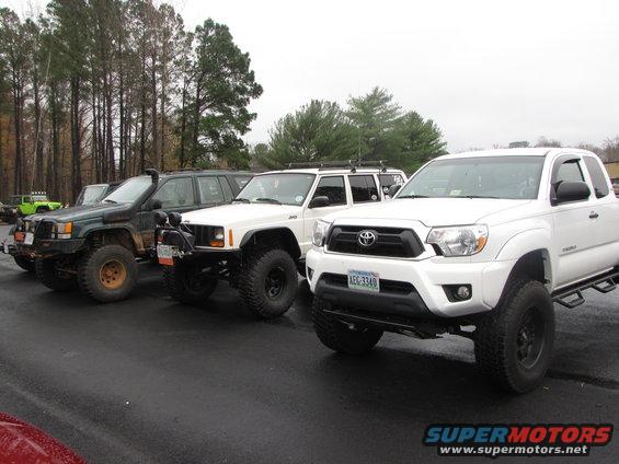 White Toyota Tacoma truck in front of modified Jeep SUVs
