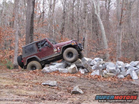 Maroon Jeep Wrangler TJ climbing over rocks off-road