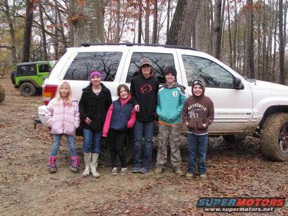 White Jeep Grand Cherokee side view with children standing in front