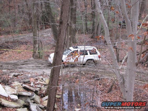 White SUV navigating a muddy forest trail
