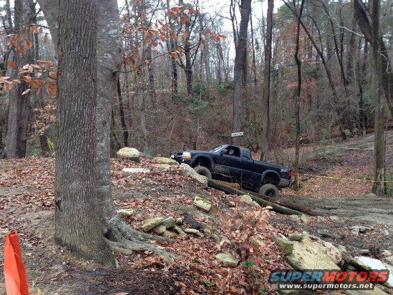 Black pickup truck navigating a steep, rocky off-road trail