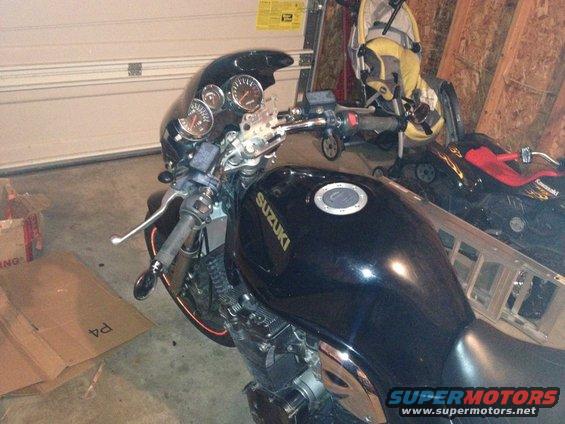 Black Suzuki motorcycle in garage with gauges and handlebars visible