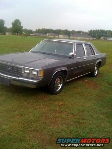 Dark gray Ford Crown Victoria parked on grass. Front end visible