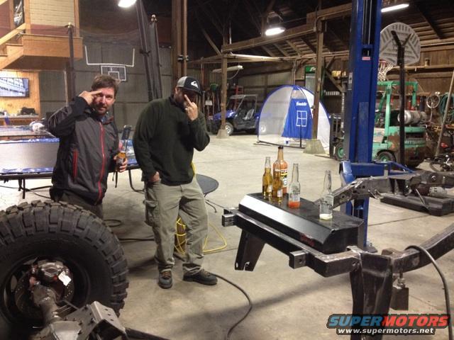 Garage scene with two men, large tire, and vehicle frame