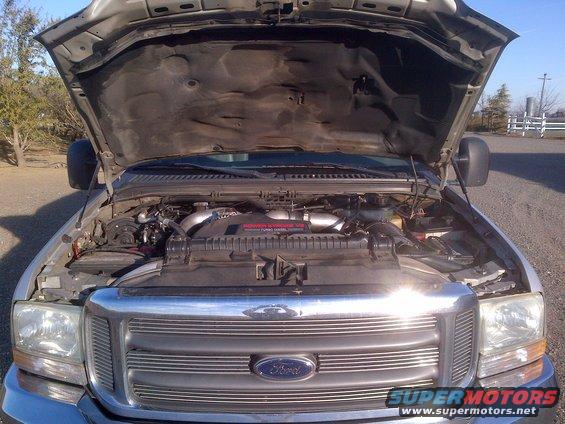 Ford Super Duty truck engine bay with hood open. Chrome grille visible