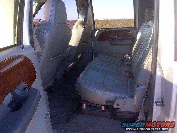 Interior of a truck showing front and rear seats. Wood trim on door panel