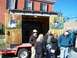 1971 Ford Ranchero - A trailer with rustic wooden doors painted with cartoon figures and text is displayed outdoors with people gathered around.