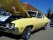 1971 Ford Ranchero - A yellow coupe, possibly a 1970 model, is displayed with its hood open, next to other vehicles.