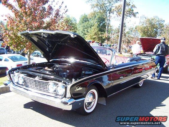 Black 1960 convertible with hood open, showing engine. Whitewall tires