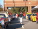 1971 Ford Ranchero - A line of cars is parked outside a brick building, with people gathered around them on a sunny day.