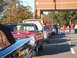 1971 Ford Ranchero - A row of vintage automobiles are parked on a street, with people milling around in the background.