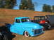 1971 Ford Ranchero - A bright blue pickup truck is parked next to a black truck with its hood open.