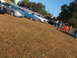 1971 Ford Ranchero - Several cars are parked on a grassy slope, with people milling around them.