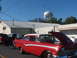 1971 Ford Ranchero - A classic red and white sedan is displayed with its hood up, alongside other vehicles under a clear blue sky.