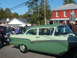1971 Ford Ranchero - A two-tone green sedan is parked at an outdoor gathering with other vehicles and people.