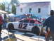 1971 Ford Ranchero - A race car is displayed on a checkered mat in front of a building with people around.