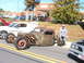 1971 Ford Ranchero - A heavily modified and rusted hot rod sits on display at a car show, with other vehicles nearby.