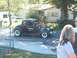 1971 Ford Ranchero - A black hot rod coupe with a prominent engine is parked near a house, with other vehicles visible in the background.