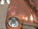 1971 Ford Ranchero - Close-up of a heavily rusted vehicle fender a pink and gold pinstripe flame graphic and a clear headlight. The word 'SUPERMOTORS' is visibl…