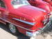 1971 Ford Ranchero - Rear view of a red coupe with distinctive chrome trim and wire wheels, parked next to another red vehicle.
