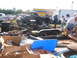 1971 Ford Ranchero - A black truck chassis with a trailer is displayed at an outdoor market, surrounded by parts and other vehicles.
