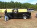 1971 Ford Ranchero - A man poses with a shiny black vintage pickup truck on a grassy field with portable toilets and a trailer behind it tow.