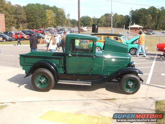 Green pickup truck with black fenders and wheels, viewed from the side