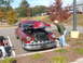 1971 Ford Ranchero - A man inspects the engine of a classic red coupe parked in a lot.