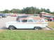 1971 Ford Ranchero - A light blue station wagon with surfboards on its roof rack is parked in a lot, showing signs of rust on its roof.