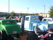 1971 Ford Ranchero - A light blue pickup truck and a green hot rod are parked at an outdoor car show.