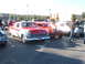1971 Ford Ranchero - A red and white 1956 Ford Fairlane Crown Victoria is parked at an outdoor car show with other vehicles.