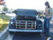 1971 Ford Ranchero - A person stands next to a vintage black pickup truck with a wooden bed at an outdoor car show.