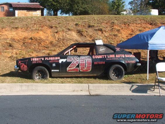 Black stock car with red number 20 on the side, advertising Tommy's Plumbing and County Line Auto Sales