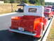 1971 Ford Ranchero - A red pickup truck with a silver cab is parked next to other vehicles on a sunny day.
