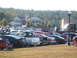 1971 Ford Ranchero - A gathering of vehicles in a parking lot under a clear sky with trees in the background.