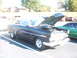 1971 Ford Ranchero - A dark-colored 1950s Ford with its hood up is parked in a lot next to a green car.