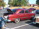 1971 Ford Ranchero - This red sedan has its trunk and hood open, parked at an outdoor event with other vehicles present.
