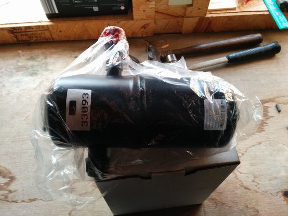 Black automotive part in plastic wrap with label 33093