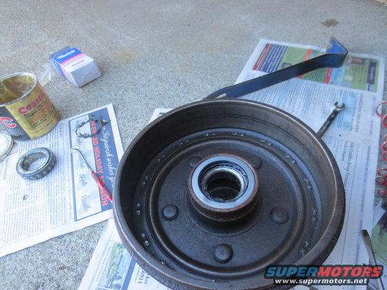 Brake drum with bearing and can of grease on newspaper
