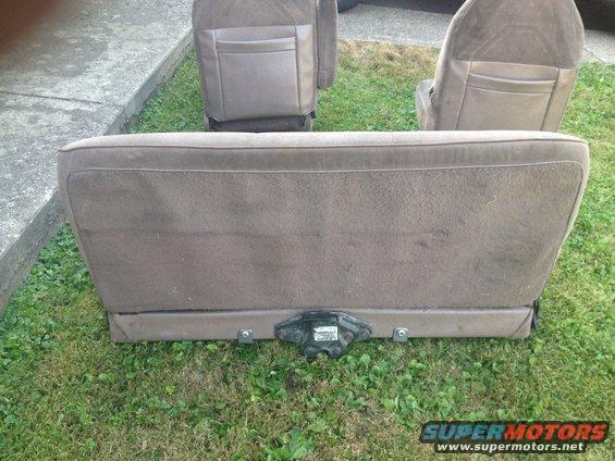 Brown fabric car seats removed from a vehicle, sitting on grass