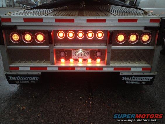 Rear of a trailer with many red and amber lights, license plate 495 702, and Reitnouer mudflaps